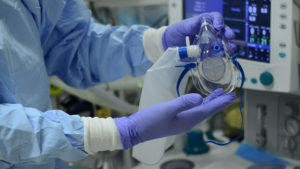 Medical person with blue surgical gloves is showing the POM Mask