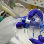 Procedural Oxygen Mask held by hands with blue surgical gloves